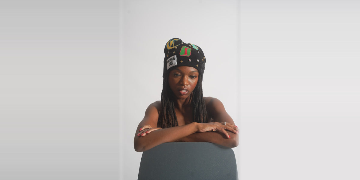 Model in the black CIC Gemstone Beanie, arms folded on a chair